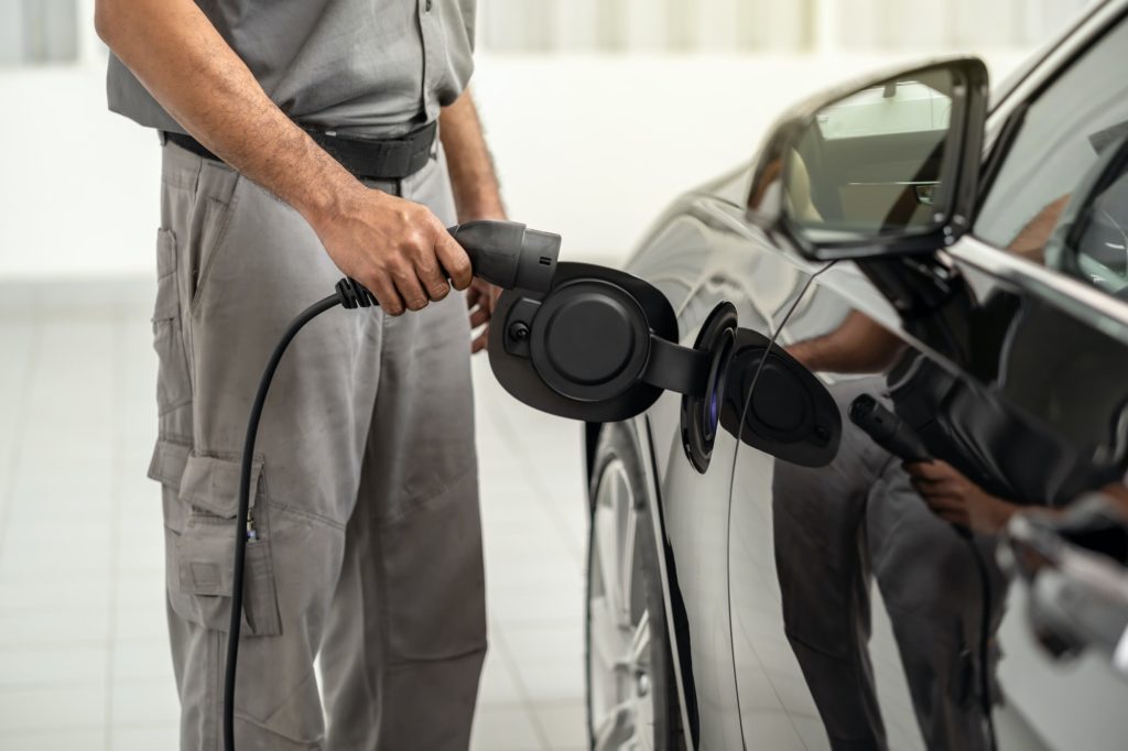 Closeup asian Technician hand is charging the electric car or EV in service center