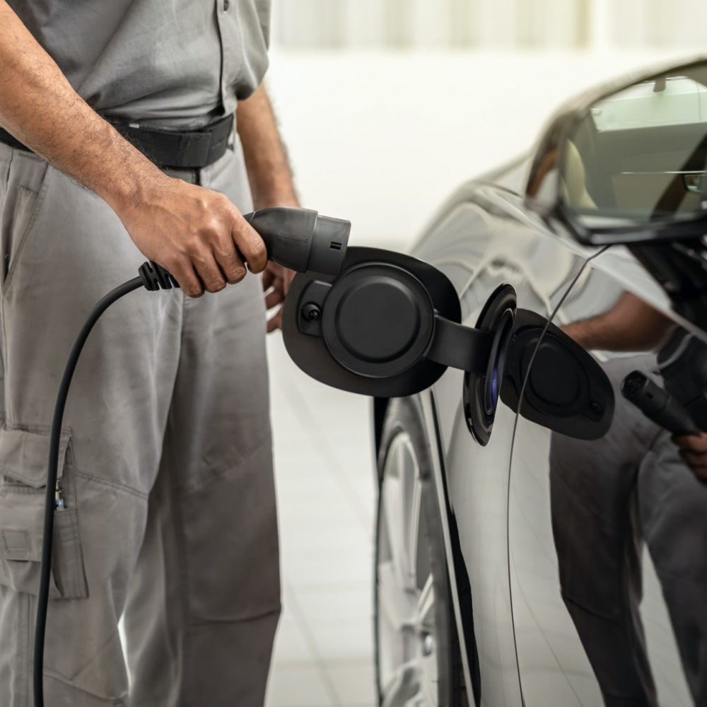 Closeup asian Technician hand is charging the electric car or EV in service center